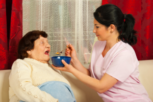 caregiver giving food to the elderly