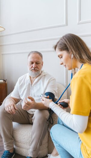 A healthcare professional checks an elderly man's blood pressure in a cozy room.
