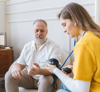 A healthcare professional checks an elderly man's blood pressure in a cozy room.