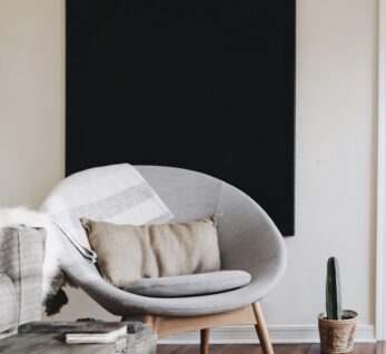 round grey moon chair with brown pillow on top