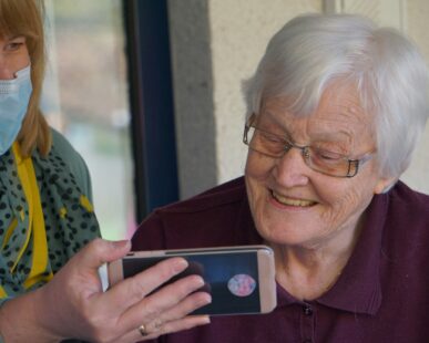 woman in brown button up shirt holding white smartphone