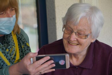 woman in brown button up shirt holding white smartphone