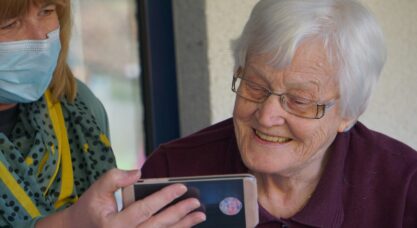 woman in brown button up shirt holding white smartphone